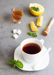 A cup of black tea with mint, honey and lemon. 
