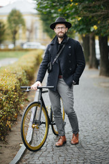 Enjoying the urban lifestyle. Young bearded man while sitting on his bicycle outdoors