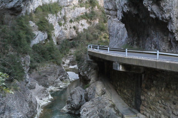 A paved road going into the Veral river canyon, with high grey rock gorge at sunset in Foz de Binies rural area, in Aragon, Spain