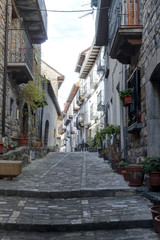 Fototapeta na wymiar A rural street of a Pyrenees mountain hamlet with stone houses with wooden balconies and dark roofs during winter in Ansó, Aragon region, Spain