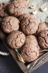 Chocolate cookies with nuts on a brown wooden tray. A old brown concrete background. Copy space for text.