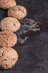 Delicious chocolate cookies with nuts on dark old concrete table. Copy space.