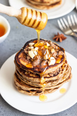 Pancakes with cashew nuts, honey, cinnamon and anise on a white plate. Perfect breakfast. Grey concrete background. Copy space.