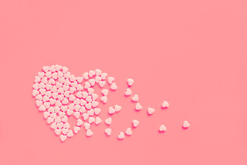 Pink heart shaped candies on a soft pink paper background. Broken heart or pearts gethering love concept. Copy space included.