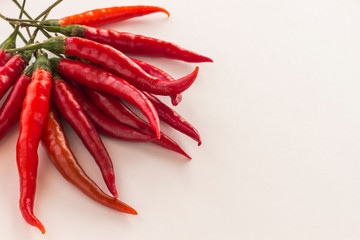 Red chili pods with green stems on white background. Top view.
