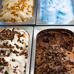 soft ice cream of different colors and tastes in metal trays