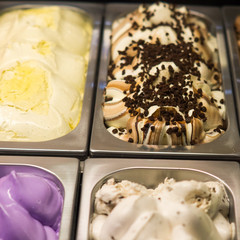 soft ice cream of different colors and tastes in metal trays