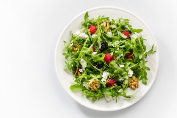 Delicious summer salad with mix of berries, nuts, goat cheese on white background. Space for text