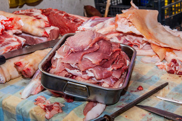 pork, from slaughter to the kitchen, raw fresh steaks ready for cooking on the grill, in a metal container, homemade, side view