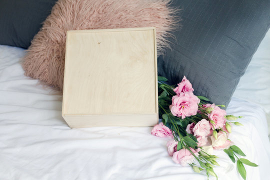 Valentines day gift with flovers. Wooden box on the bed. Copy free space for text or logo. Lifestyle image for gift. Wedding gift. Mock up wooden box