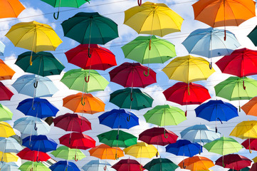 Fototapeta na wymiar umbrellas of different colors soar in the summer sky