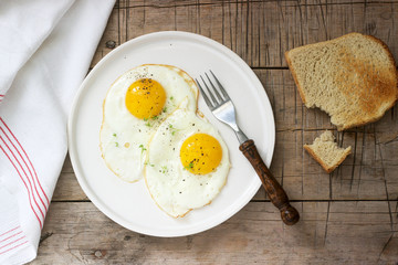 Breakfast of fried eggs, bread toasts and coffee on a wooden table. Rustic style.