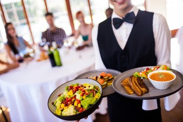Waitress holding food on plate in restaurant
