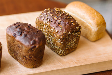 Three loaves of bread on one wooden board. Selective focus.