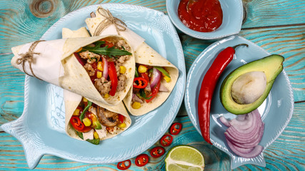 Mexican restaurant fast food - wrapped Tacos with pork meat, mushrooms and vegetables closeup at wooden desk. Mexican burritos closeup