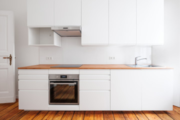 white kitchenette , newly built-in kitchen furniture frontal view with wooden worktop and board...