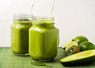 Green smoothie on green background made by avocado, lemon and kiwi.
