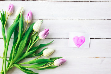 White and purple tulips on a white wooden background. Spring. International Women's Day. Valentine's Day. card with watercolor hearts,Selective focus.