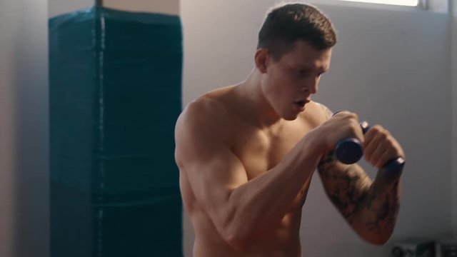 young boxer with tattoos training in gym, slow motion