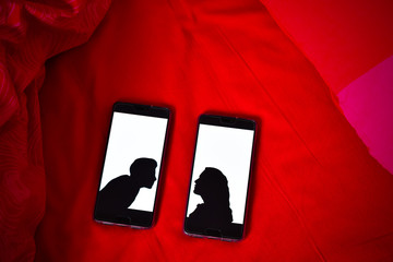 deux images d'amoureux sur des téléphones posés sur des draps rouges