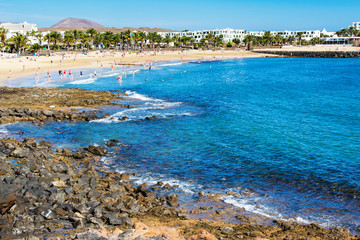 Golden sand and volcanic rocks at Las Cucharas beach, Lanzarote, Canary islands. VIew of the sea, coast and rocks, selective focus