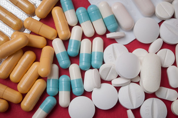 closeup of white pils and colorful capsules on red  background