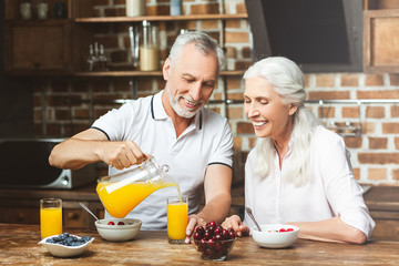 man pouring orange juice for woman