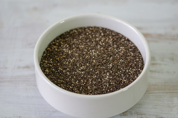 Bowl of healthy chia seeds isolated on wooden background.