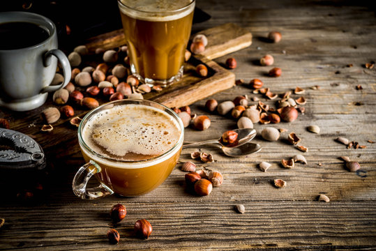 Homemade hazelnut coffee latte or cappuccino, rustic wooden background with hazelnuts, three coffee cups copy space - Powered by Adobe