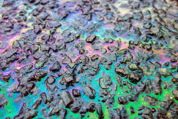 Obraz premium Rainbow Liquid Petrol Pollution Leak on Asphalt Road