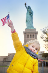 Little boy with American flag on the background of the statue of liberty in the same pose. Travel with kids. © Maria Sbytova