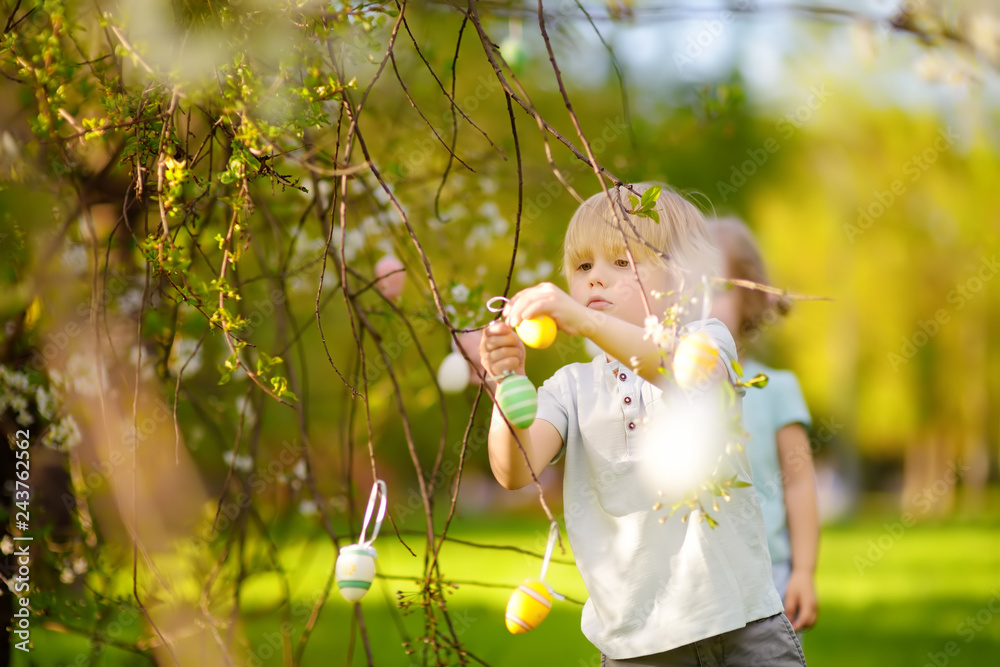 Wall mural charming little children hunts for painted eggs in spring park on easter day.