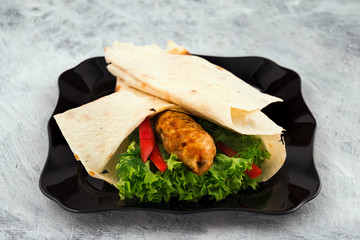 Baked kebab with minced meat. Green leaves of fresh salad with hot red pepper. Copy space. Light background. Quick delicious dinner.