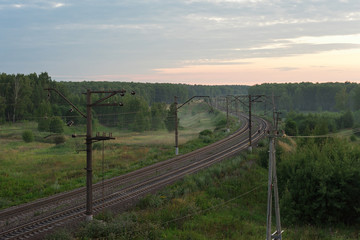 Fototapeta premium Bending railroad at dawn in a beautiful forest