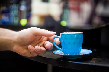 Man's hand takes a cup of a coffee to drink it