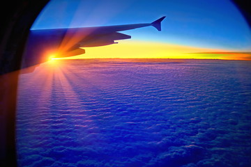  Flare light of the sunrise in the morning reflecting on the water at the island on a plane window.
