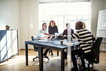 Young designers discussing paperwork together during an office m