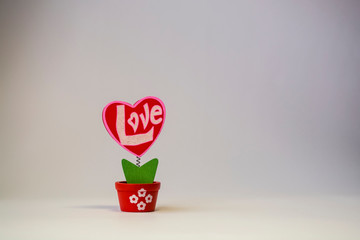 St. Valentine's Day. Red wooden heart with the inscription "love". On a spring in a pot on a white background.