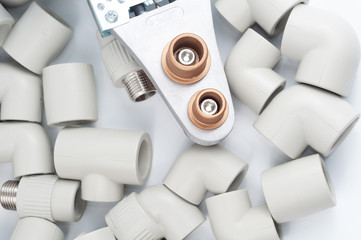 Plastic fittings and soldering iron for polypropylene pipes on a white background
