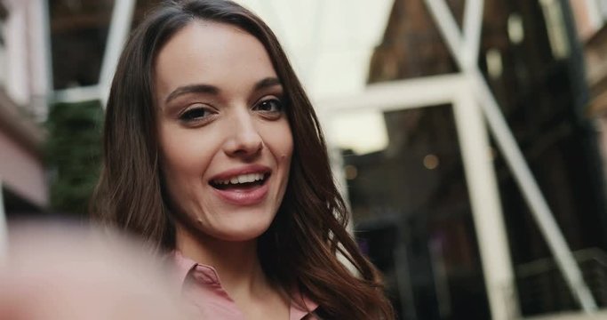 POV of the young charming brunette lady smiling cheerfully to the camera while taking selfie photos. Close up. Outside.