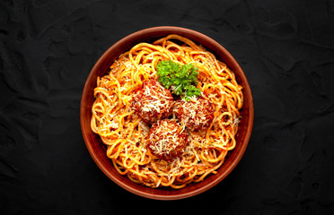 Italian pasta with tomato sauce and meatballs in a plate, dark background