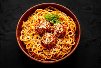 Italian pasta with tomato sauce and meatballs in a plate, dark background