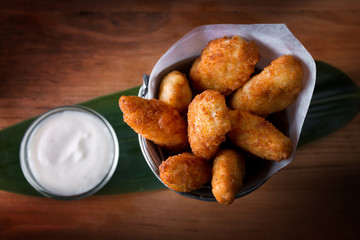 Fried nuggets with sauce, on a wooden board with a bamboo leaf, top view