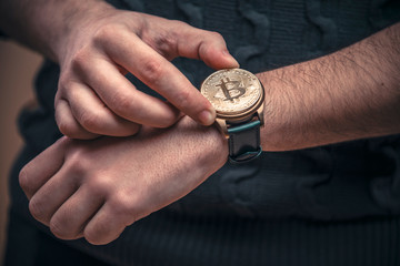 Young man's hands setting watch with a bitcoin golden penny, time to act concept