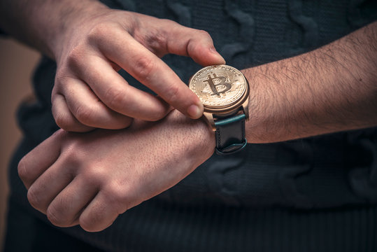 Young man's hands setting watch with a bitcoin golden penny, time to act concept
