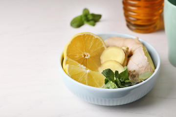 Bowl with lemon, ginger and mint on table, space for text. Cough remedies