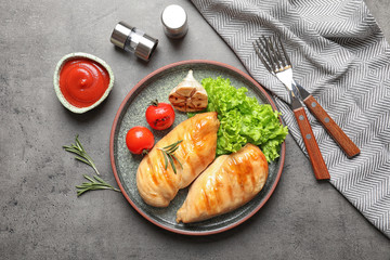 Fried chicken breasts served with sauce and garnish on grey table, top view