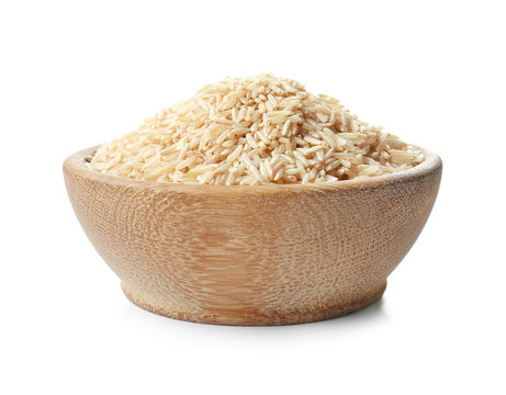 Bowl with uncooked brown rice on white background