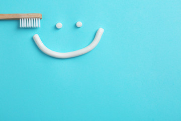 Smiling face made of toothpaste, brush and space for text on color background, top view
