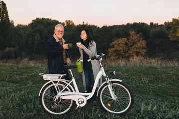 Obraz premium Thermos picnic. Ride a bike. Keep warm hot coffee from a thermos. Bicycle lifestyle. Father and daughter spend time together.
